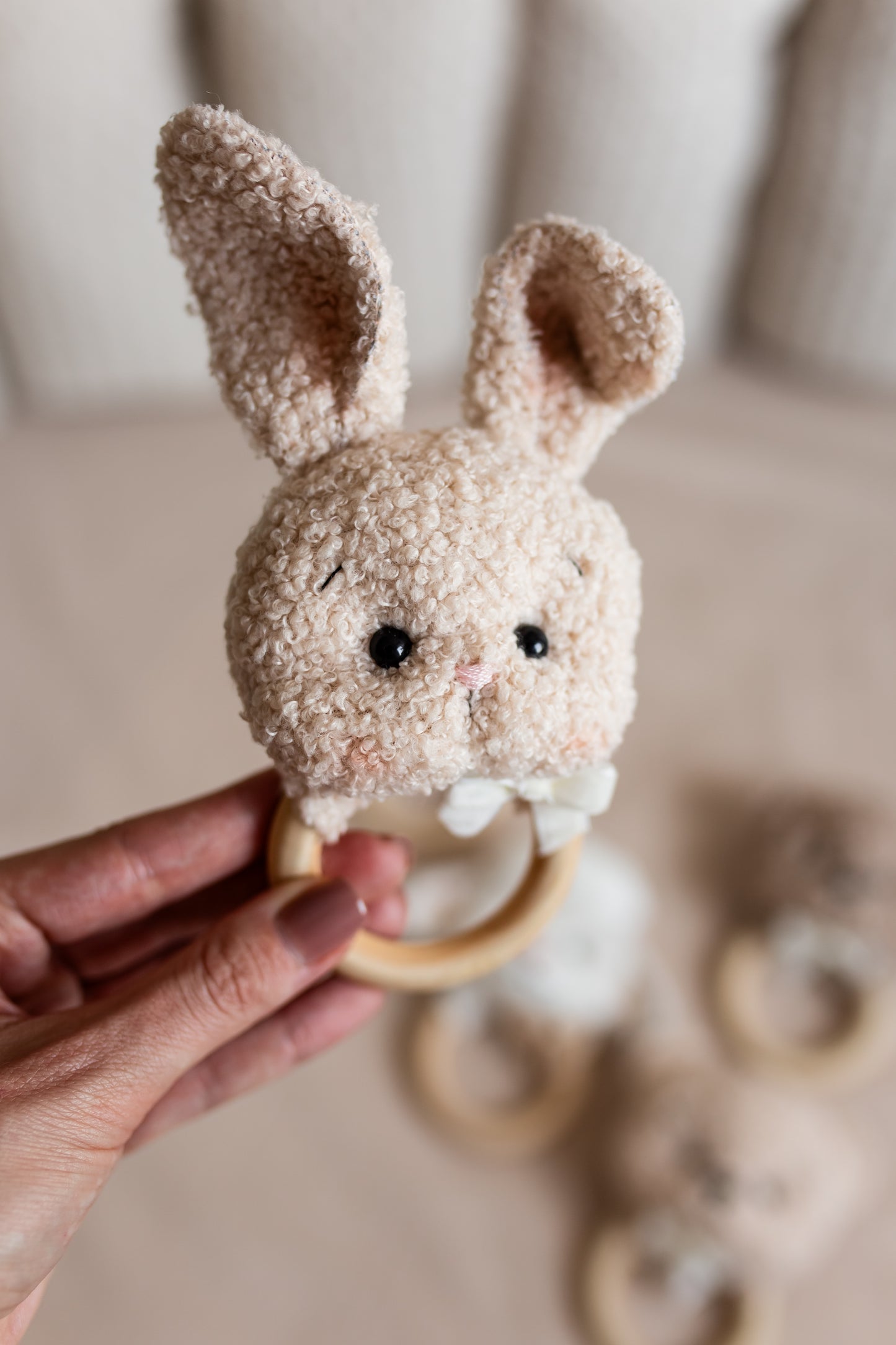 Hand holding a textured bunny rattle toy with a blurred background