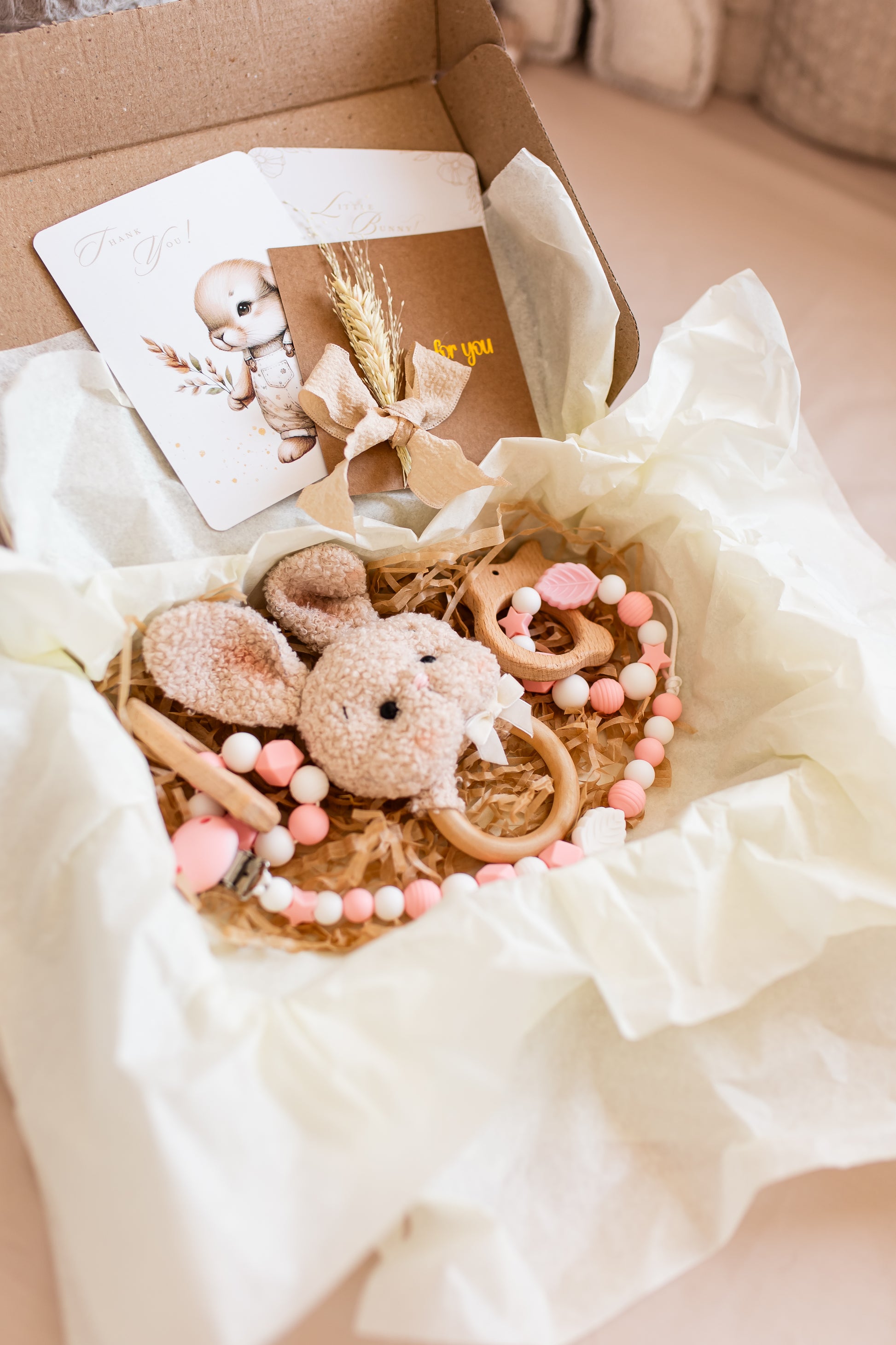 Baby gift set with plush toy, card, and decorative elements in a box.