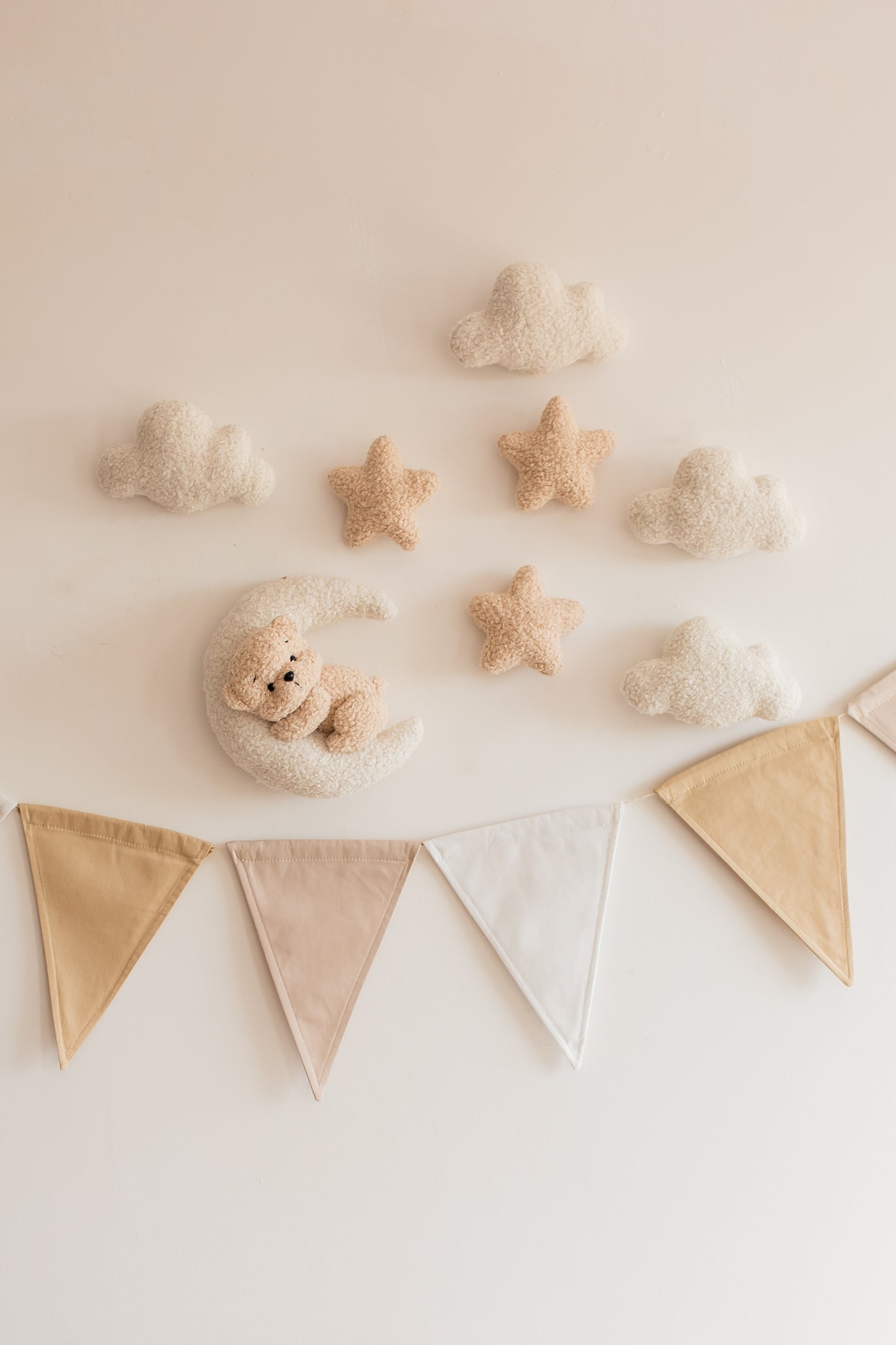 Decorative wall with soft toys, stars, and a banner on a light background