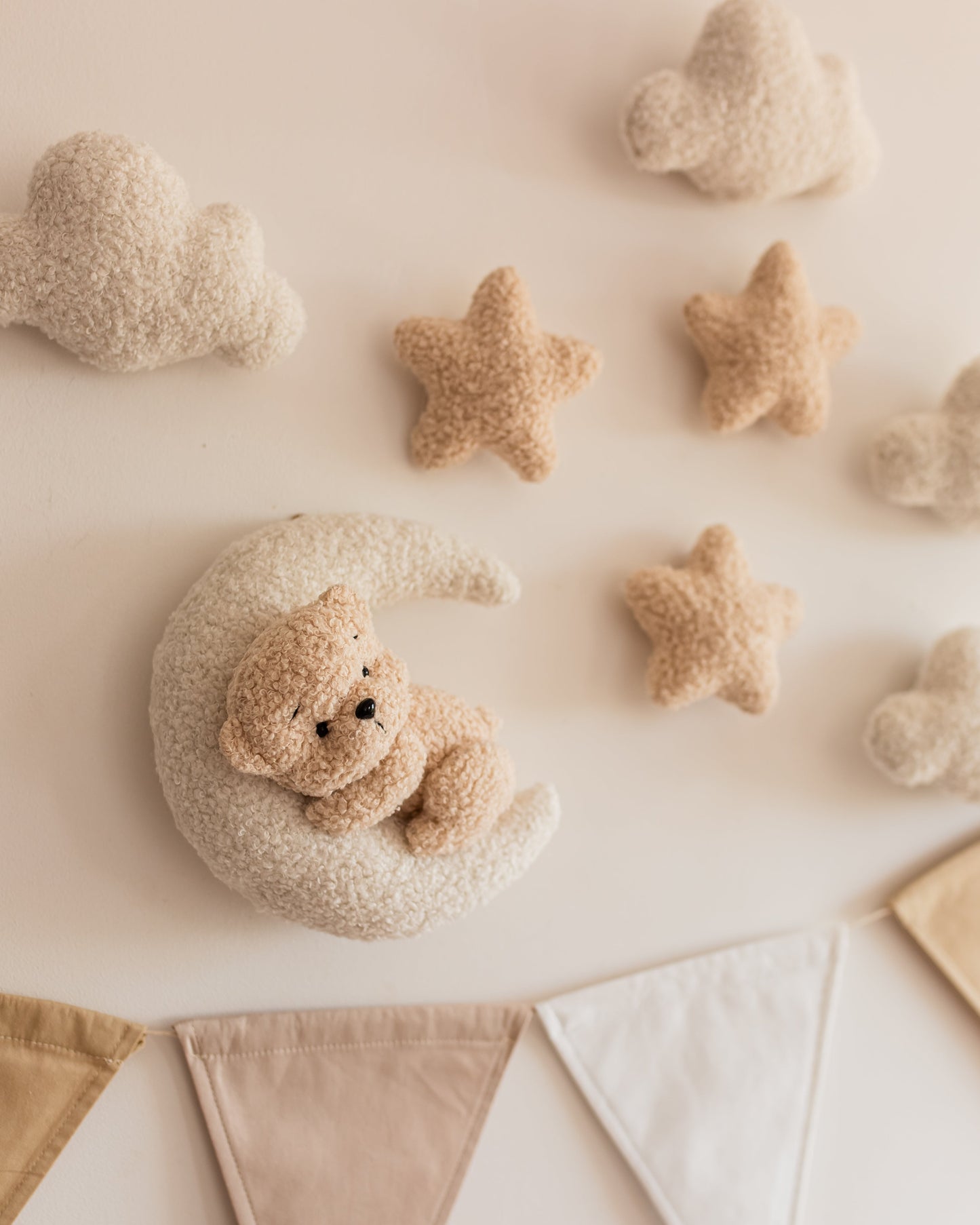 Bouclé teddy bear on the moon wall décor with clouds and stars above crib