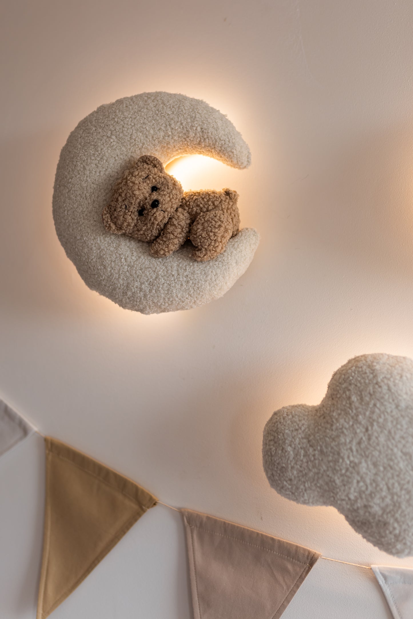 Decorative wall light shaped like a crescent moon with a teddy bear inside, mounted on a neutral wall.