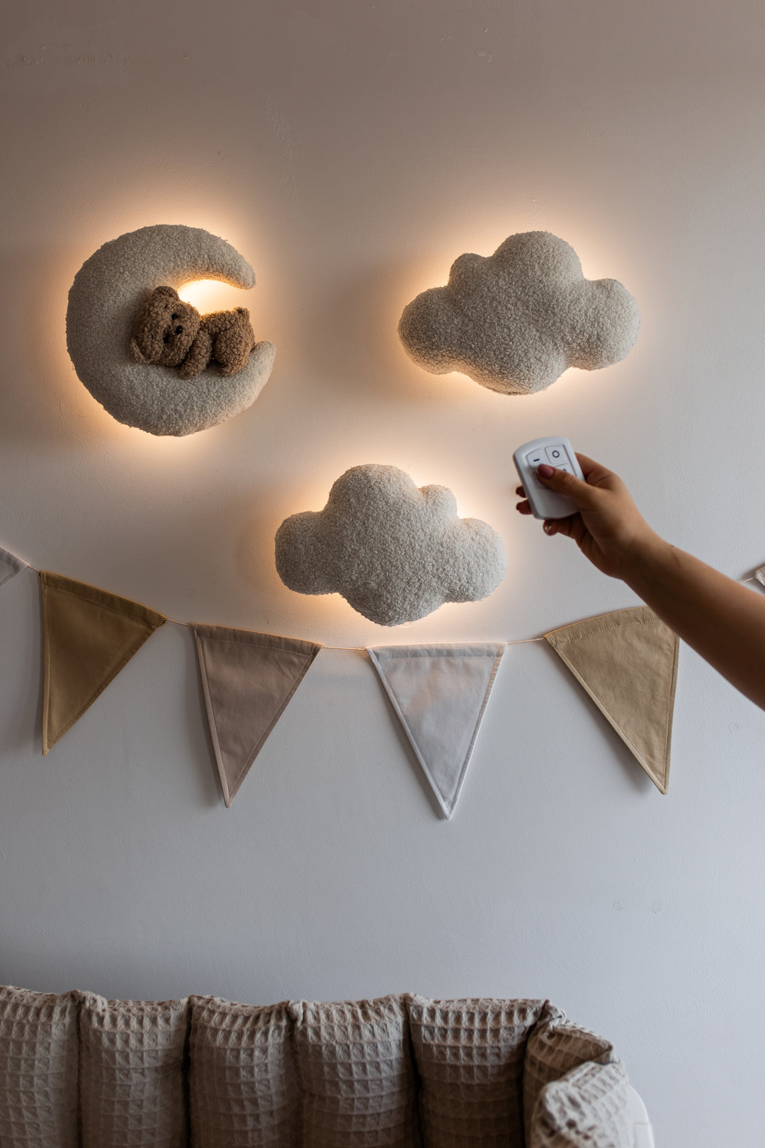 Decorative cloud-shaped wall lights with a remote control on a neutral wall.