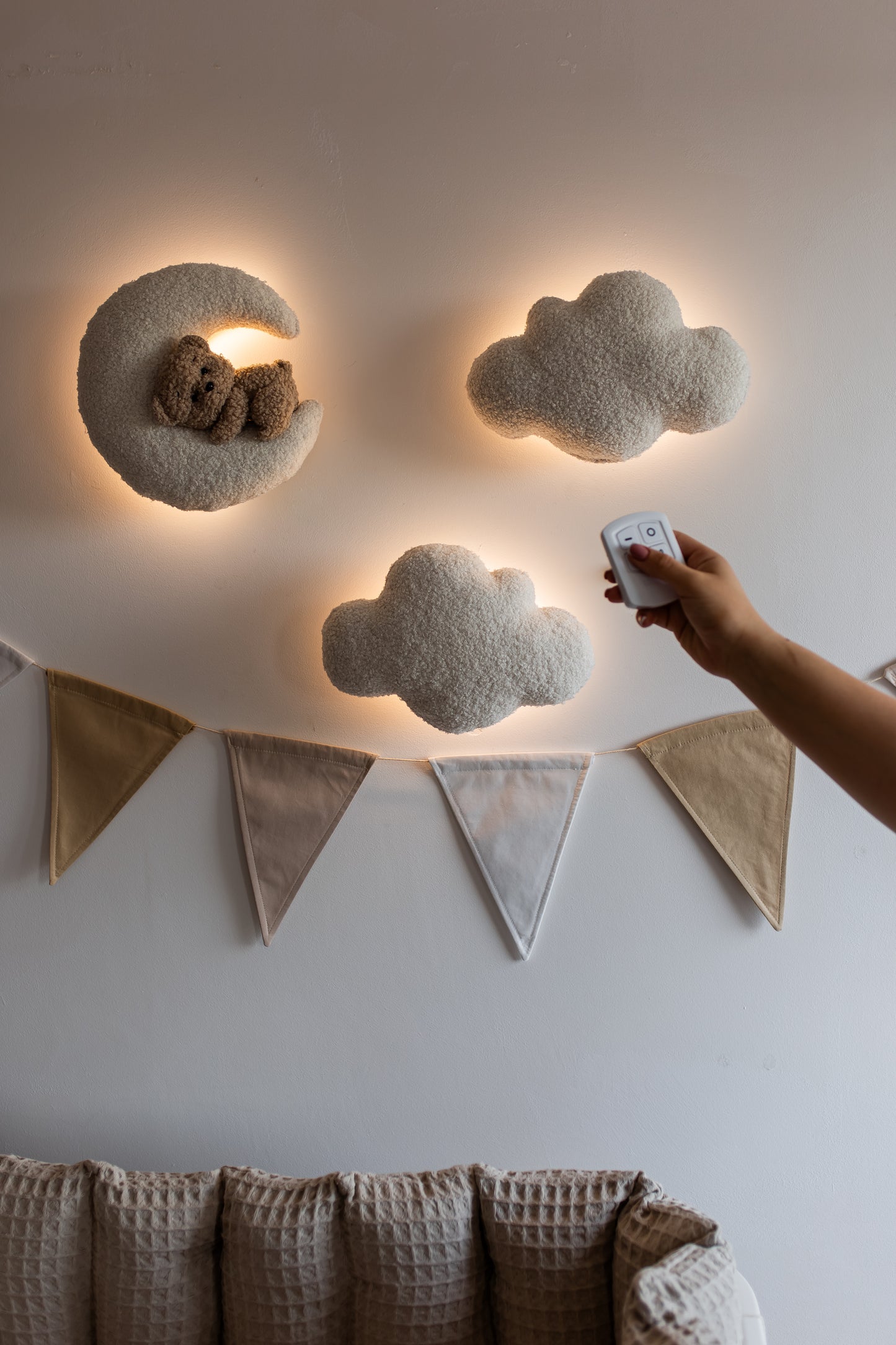 Decorative cloud-shaped wall lights with a remote control on a neutral wall.