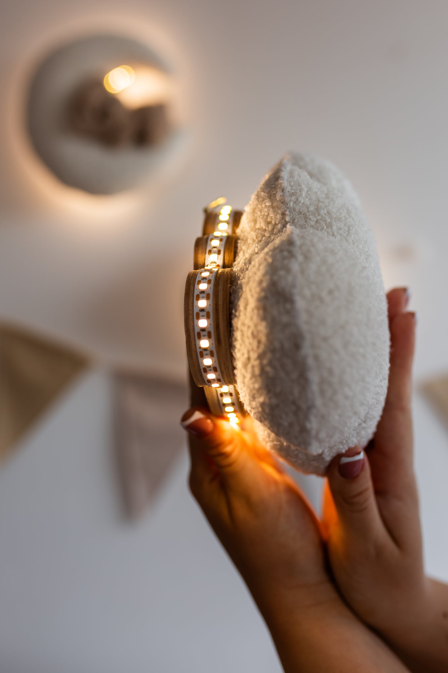 Hand holding a night light cloud with a gold base against a neutral background