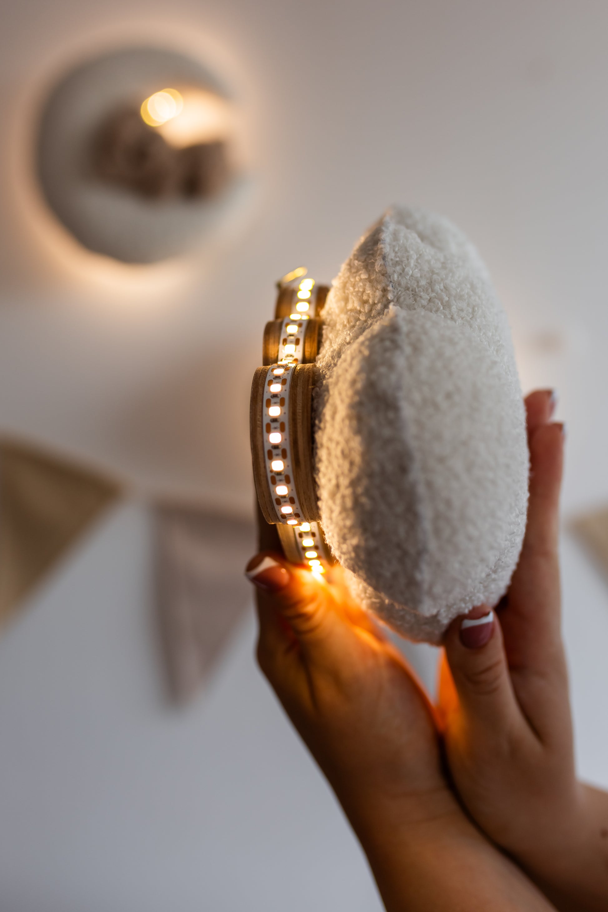 Hand holding a night light cloud with a gold base against a neutral background